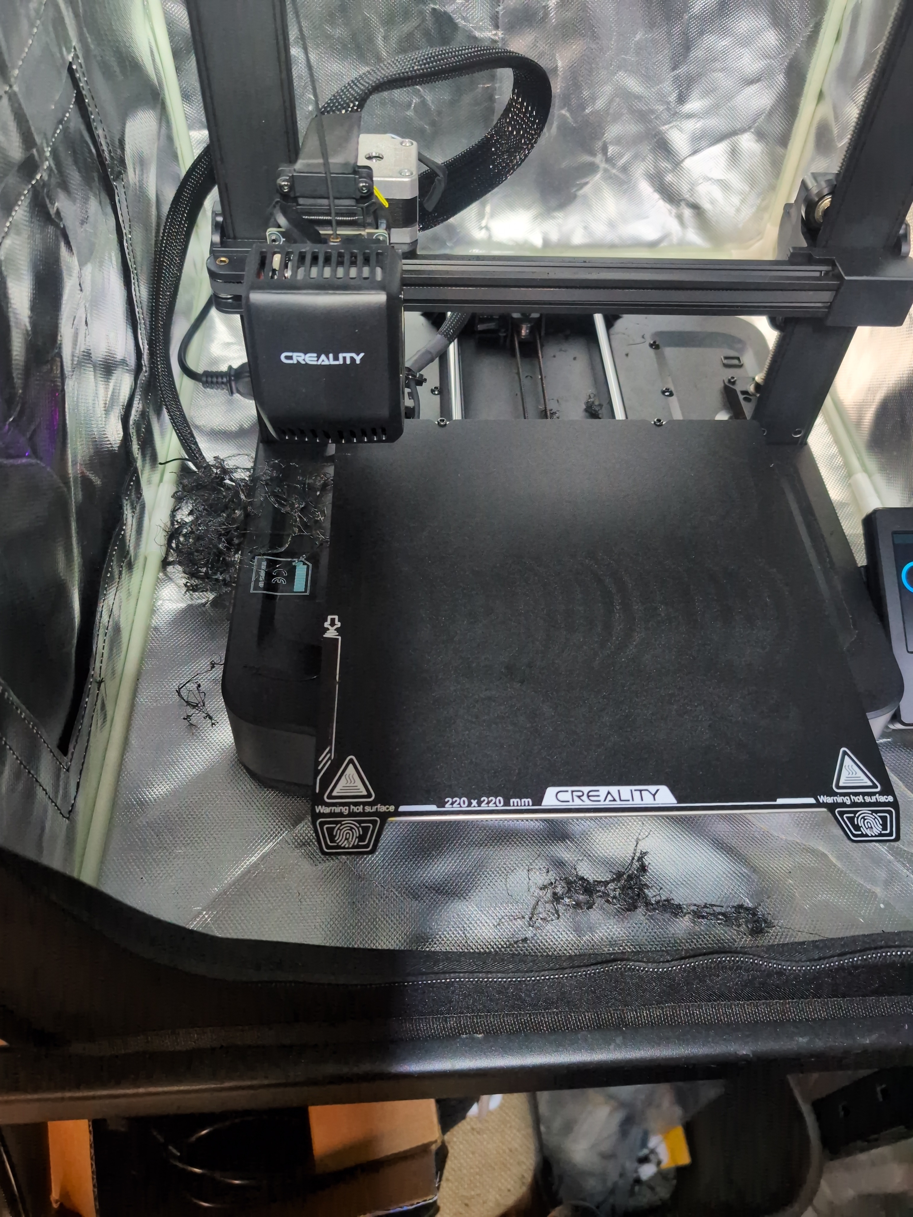 3D printer with a bare bed and plastic filament mess